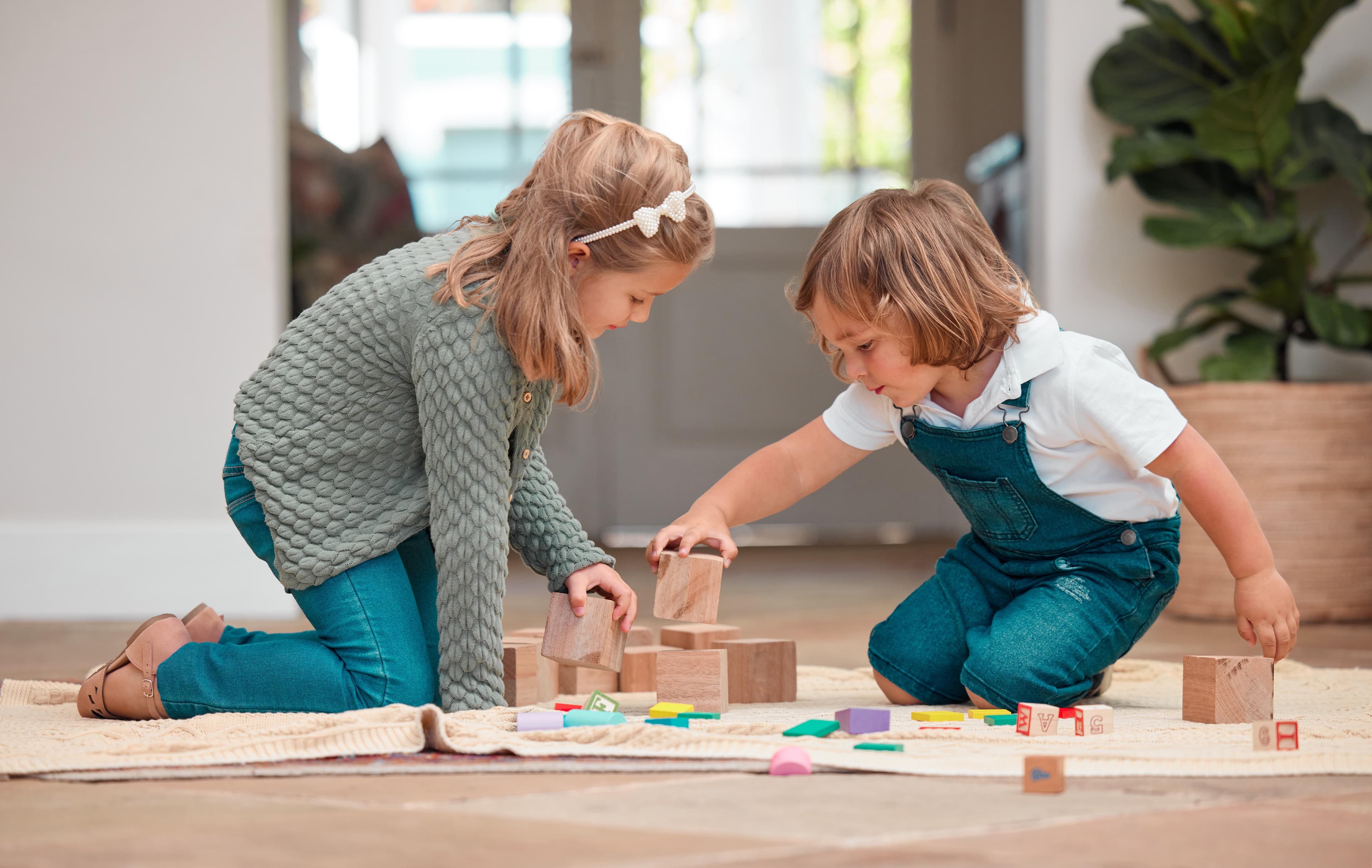 Children sitting and playing with wooden blocks on a rug