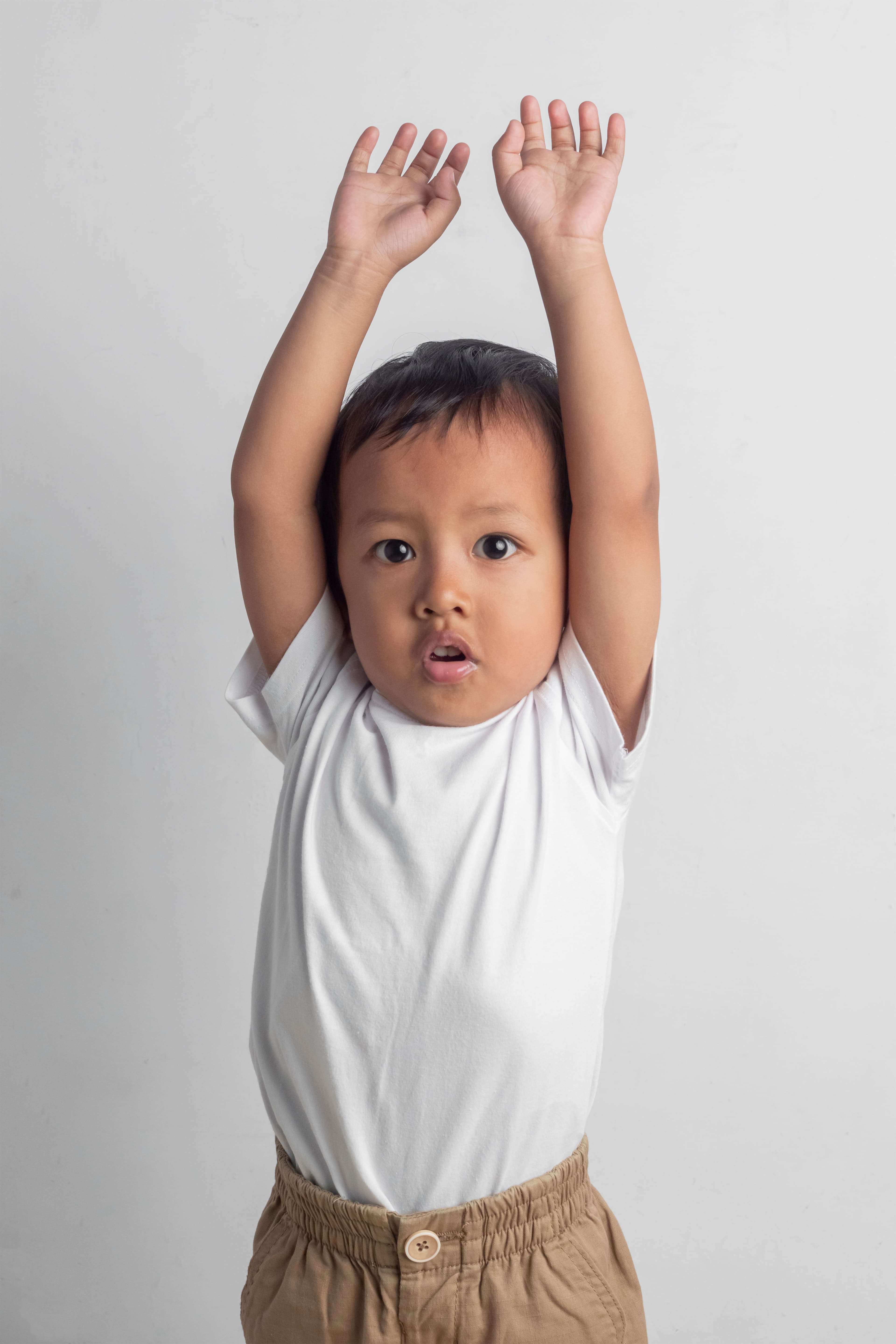 Boy in white shirt with both arms in the air.