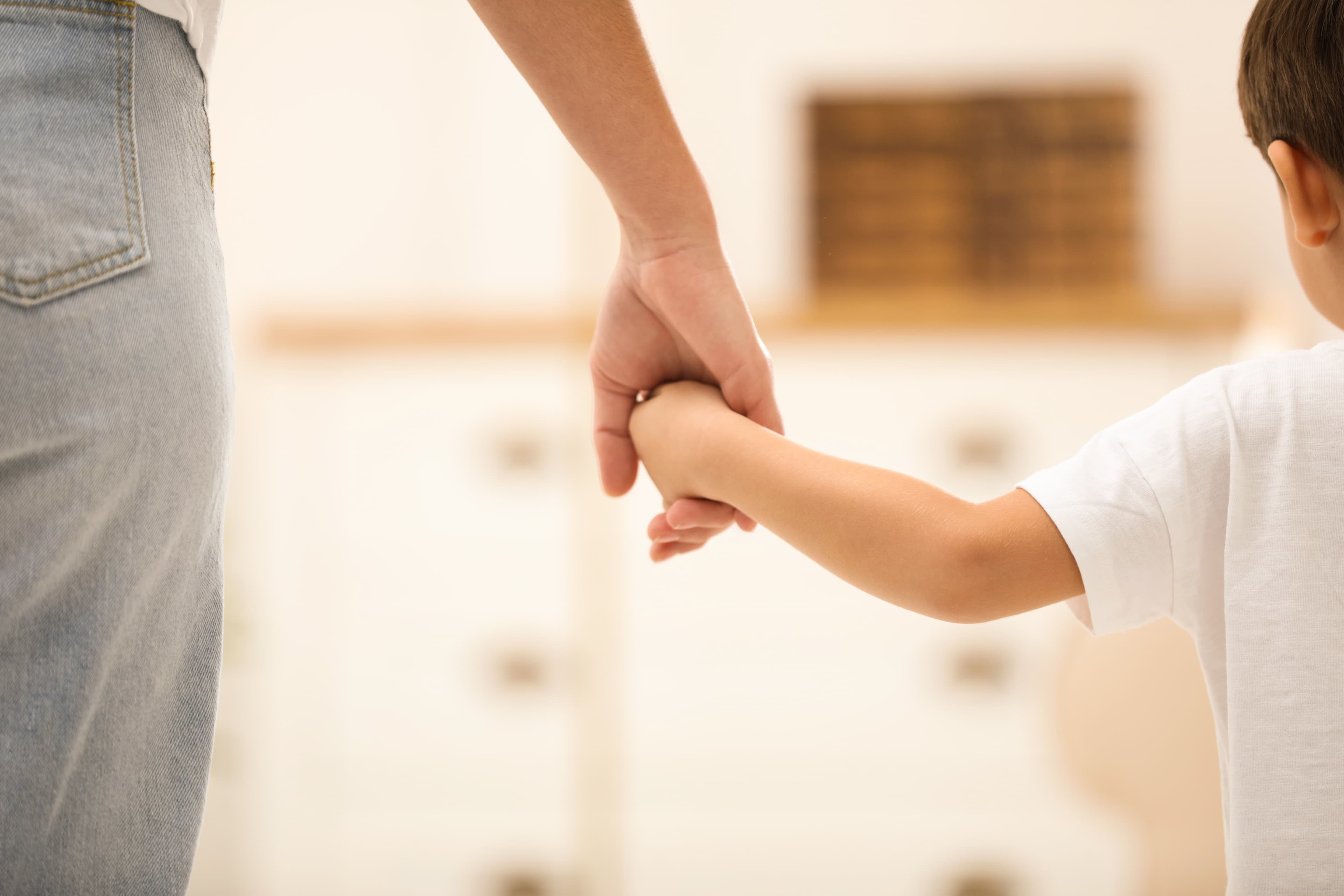 An adult and child holding hands