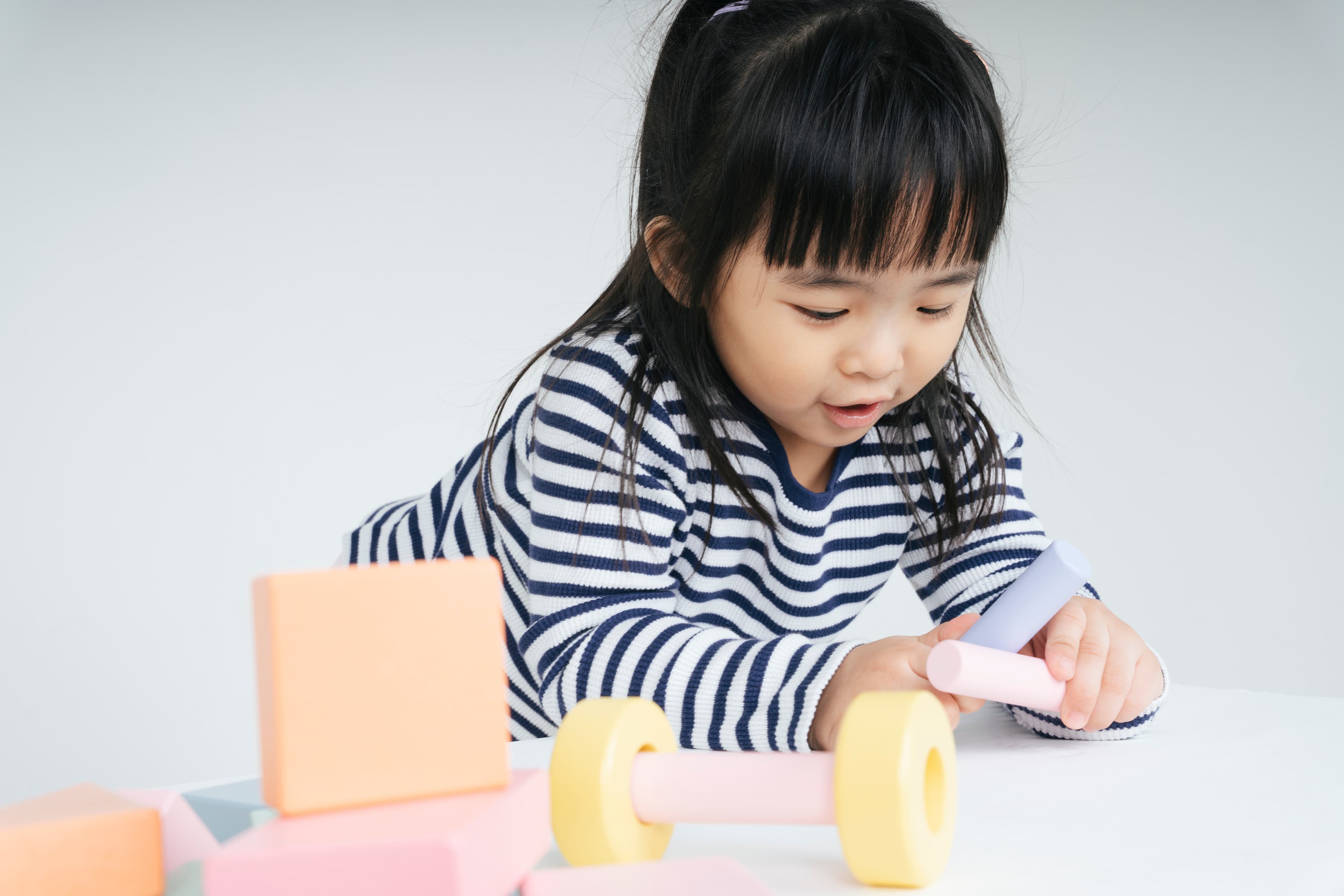A smiling child on a mat playing with colorful blocks
