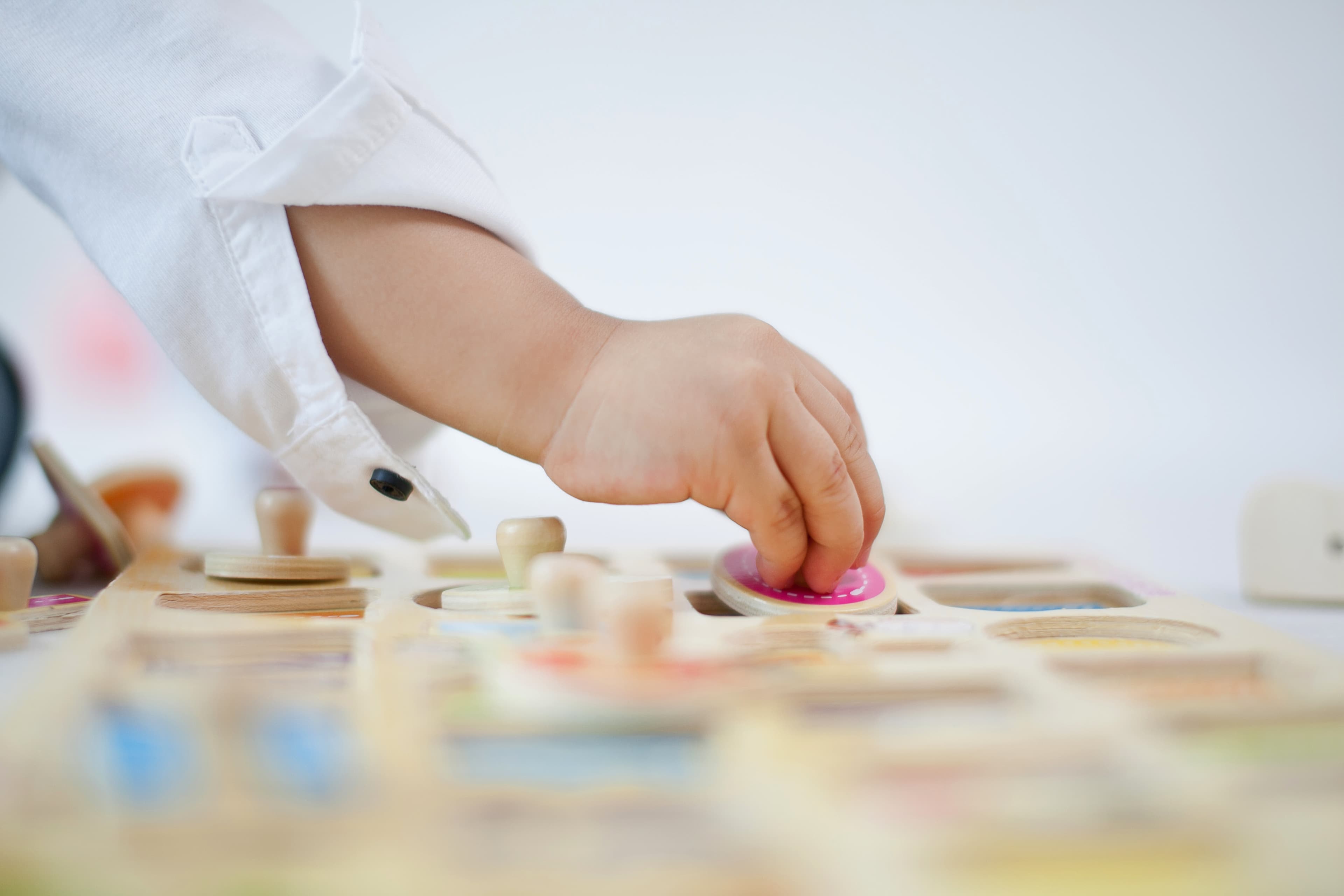 A child's hand playing with a wooden toy