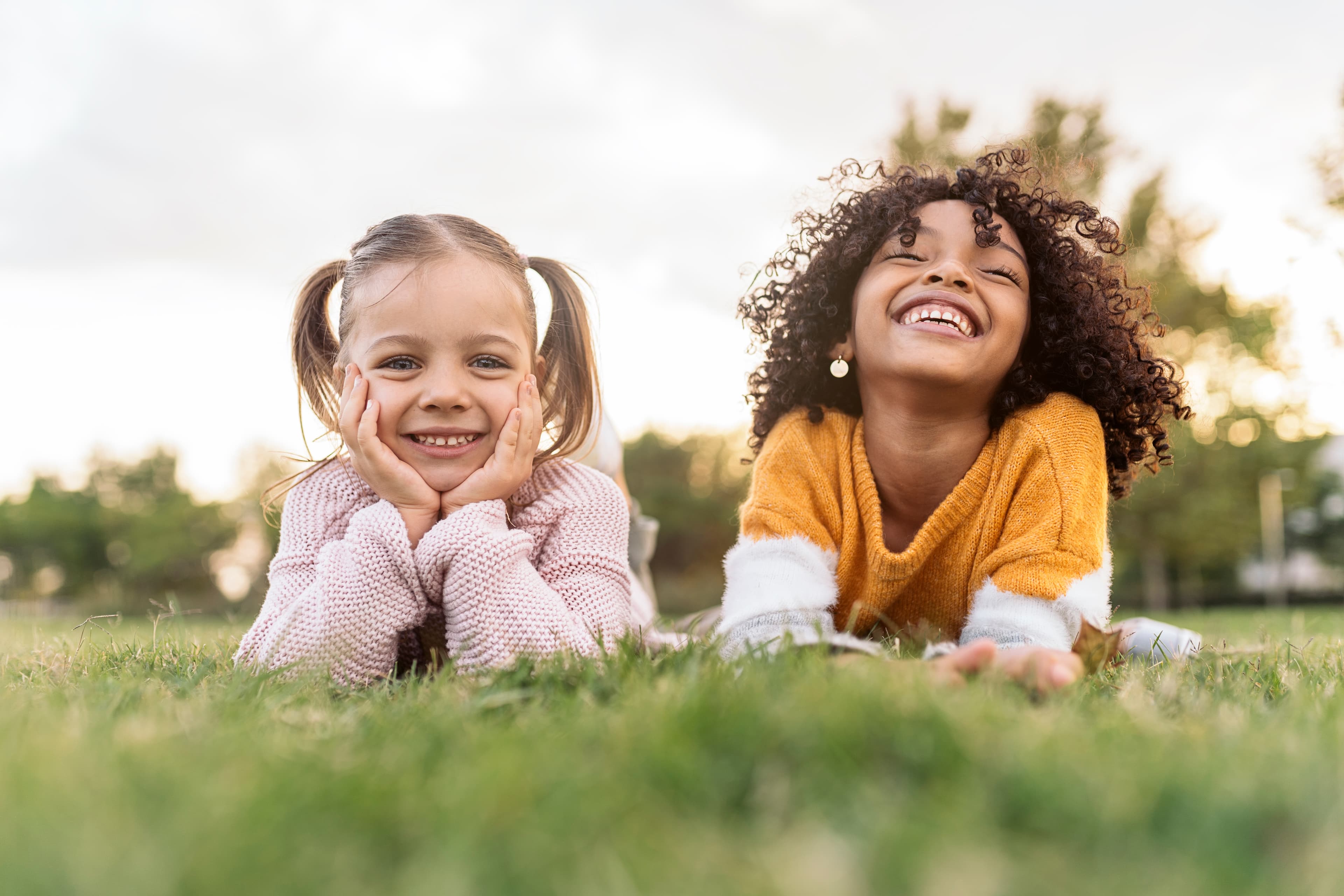 Two children smiling while lying on the grass