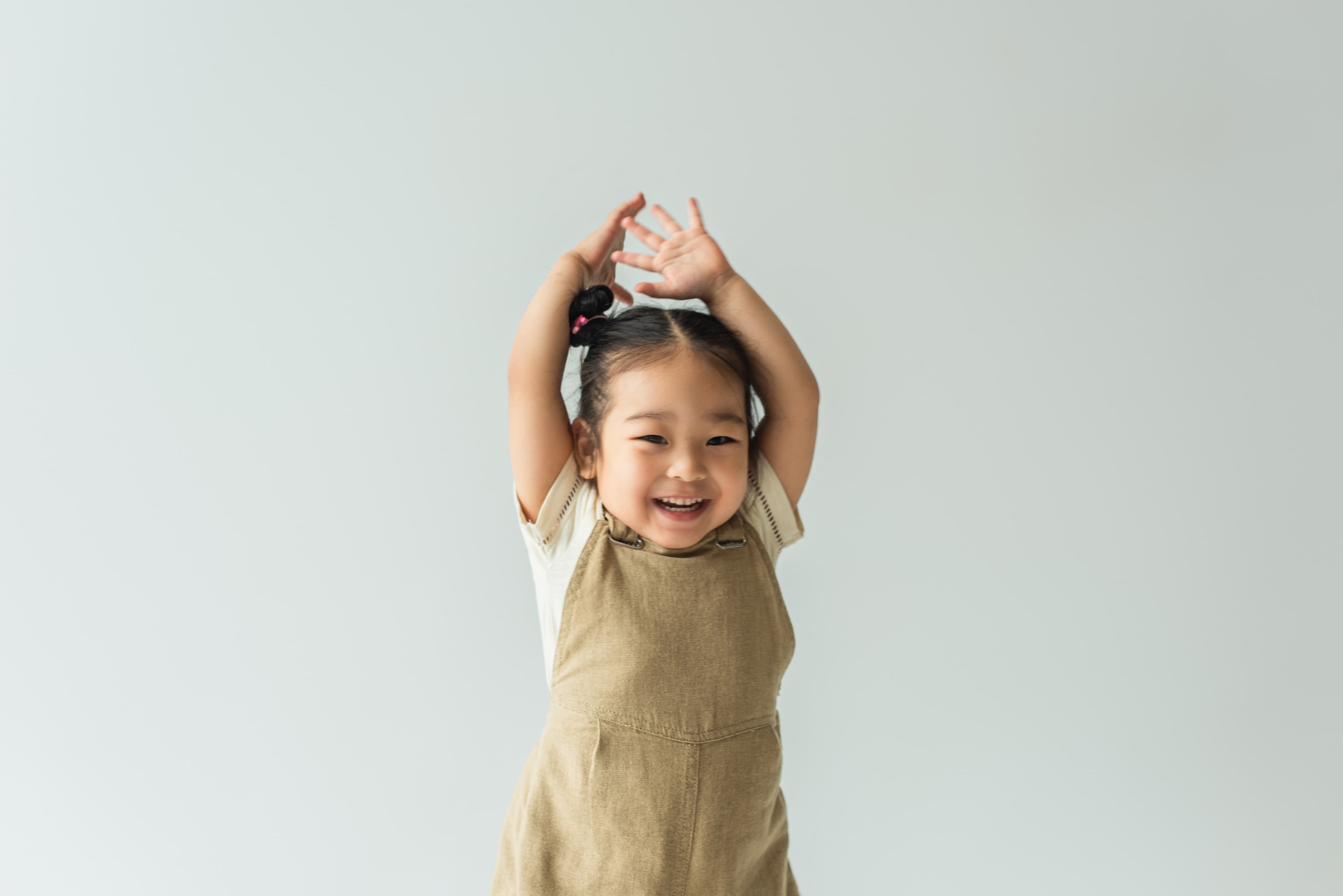 A smiling child with their hands raised in the air