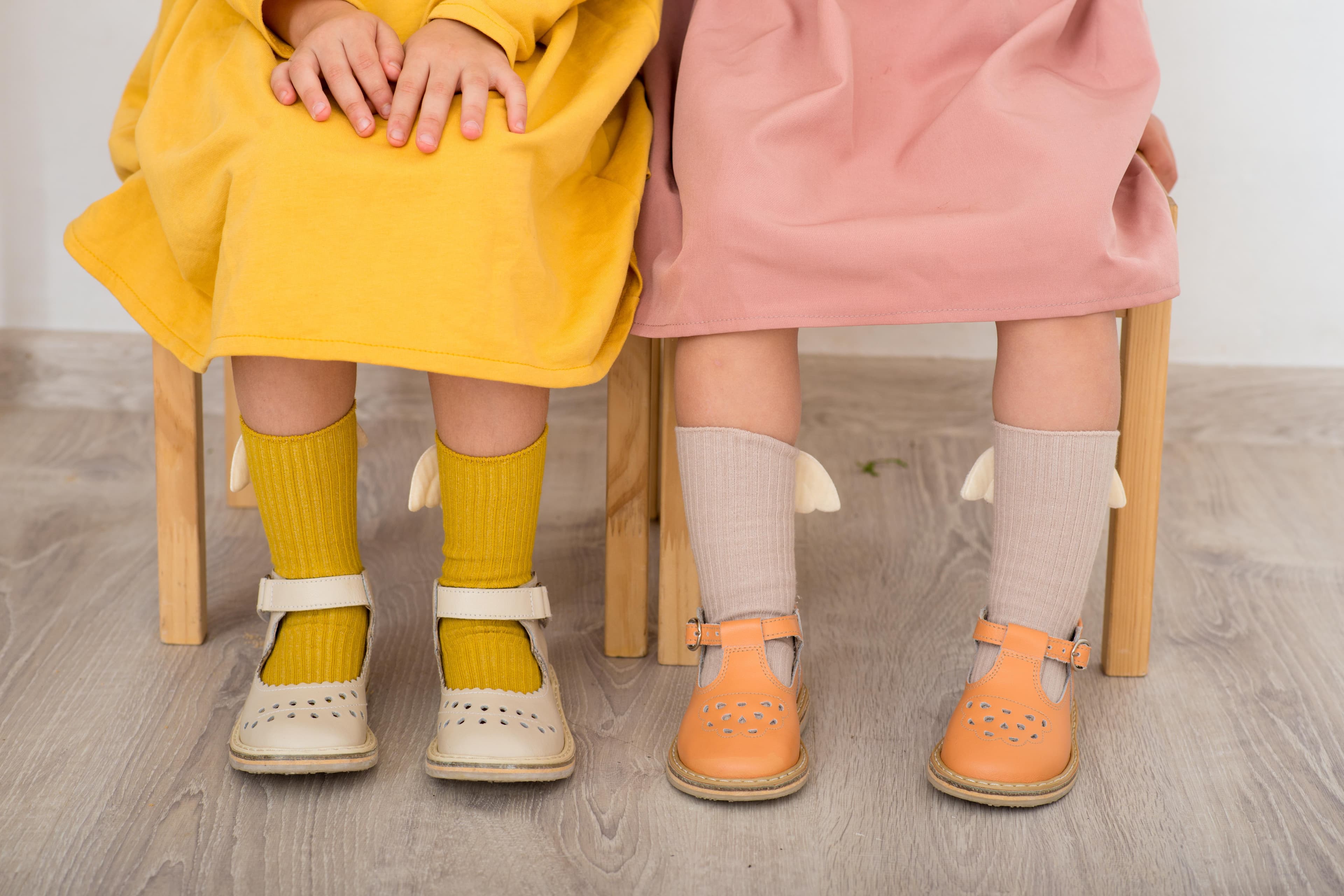 Two kids wearing color matched socks and dresses sitting next to each other