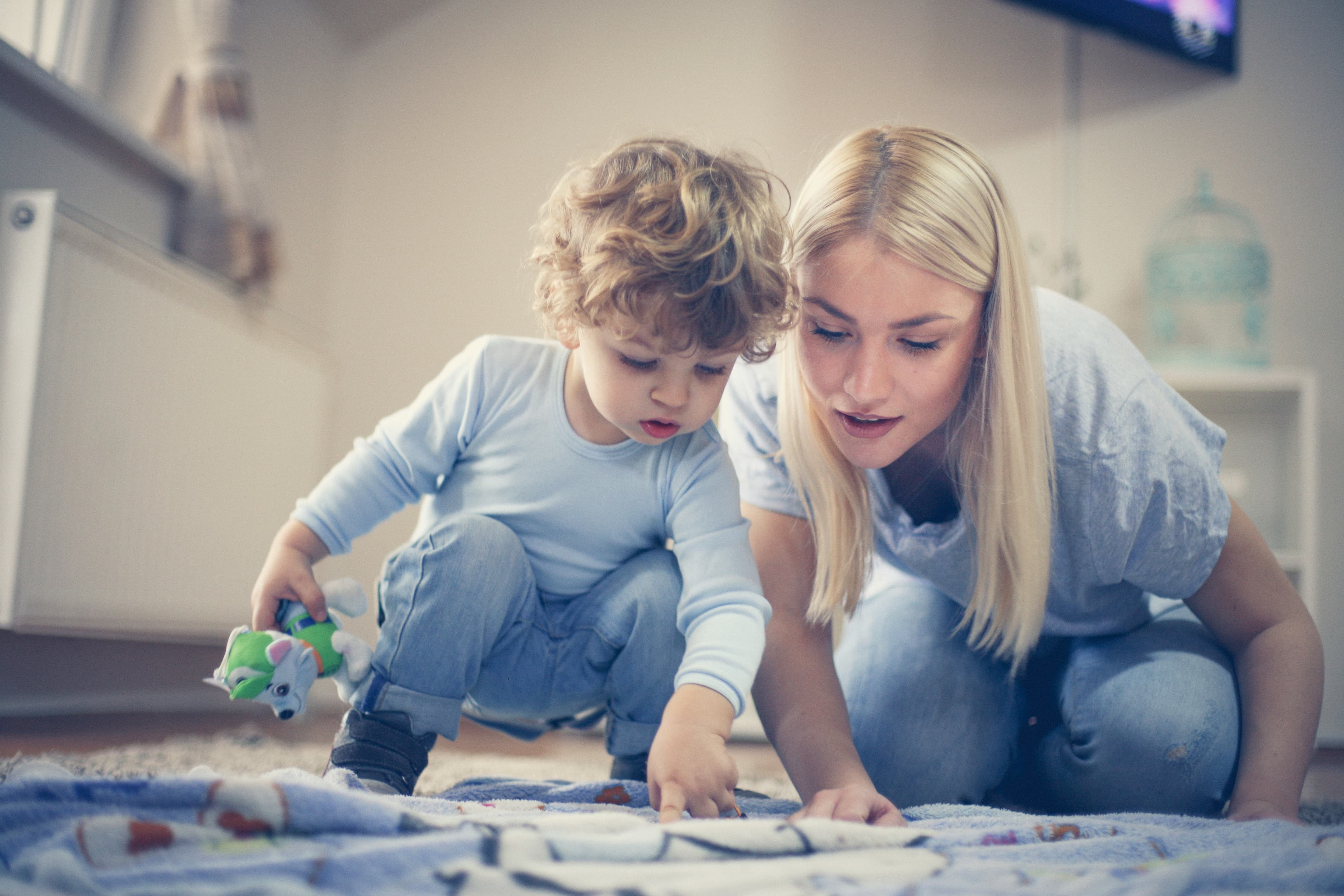 An adult and child looking at a blue blanket on the floor