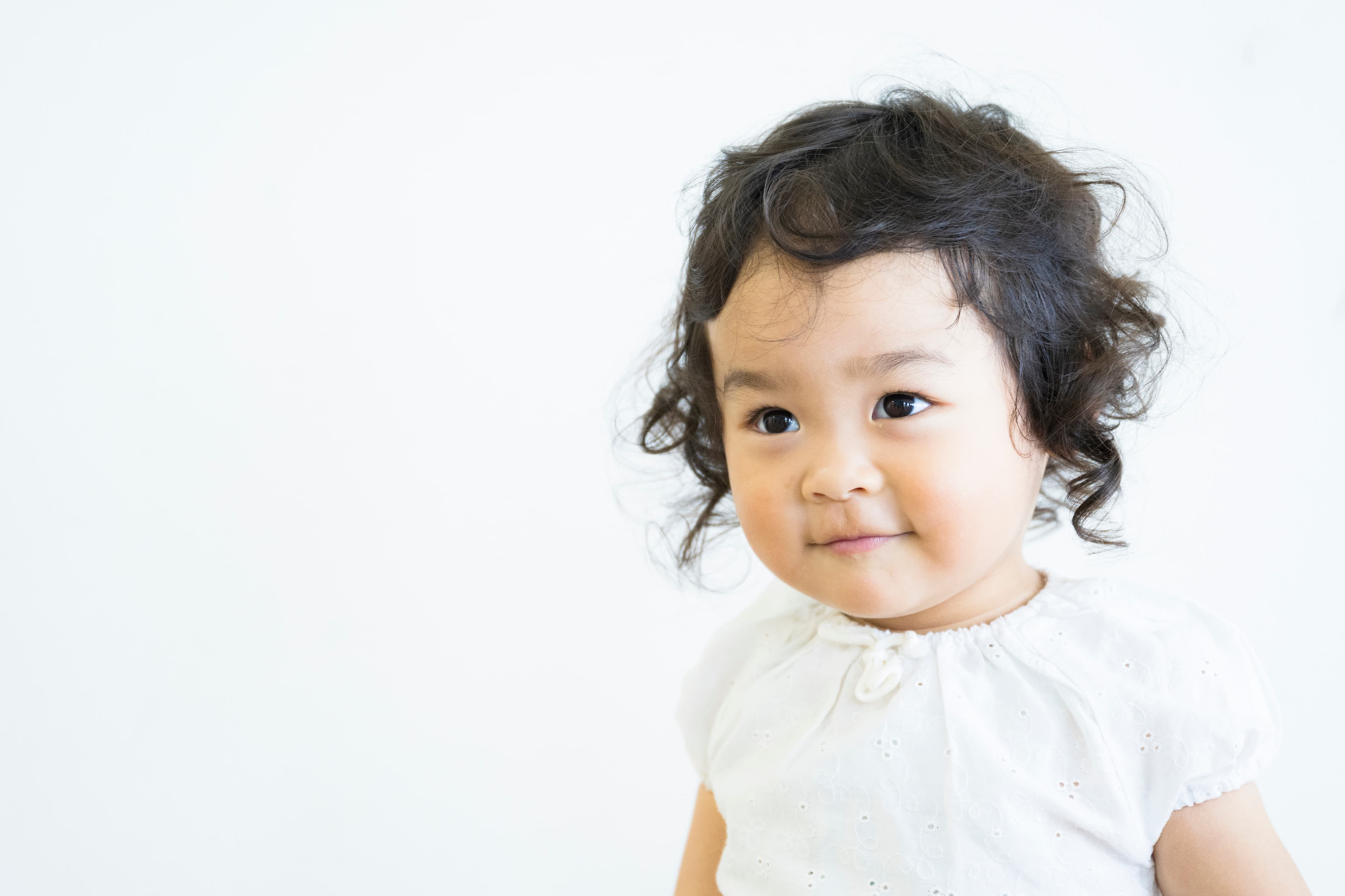 A toddler with a head of wavy hair looking to the side