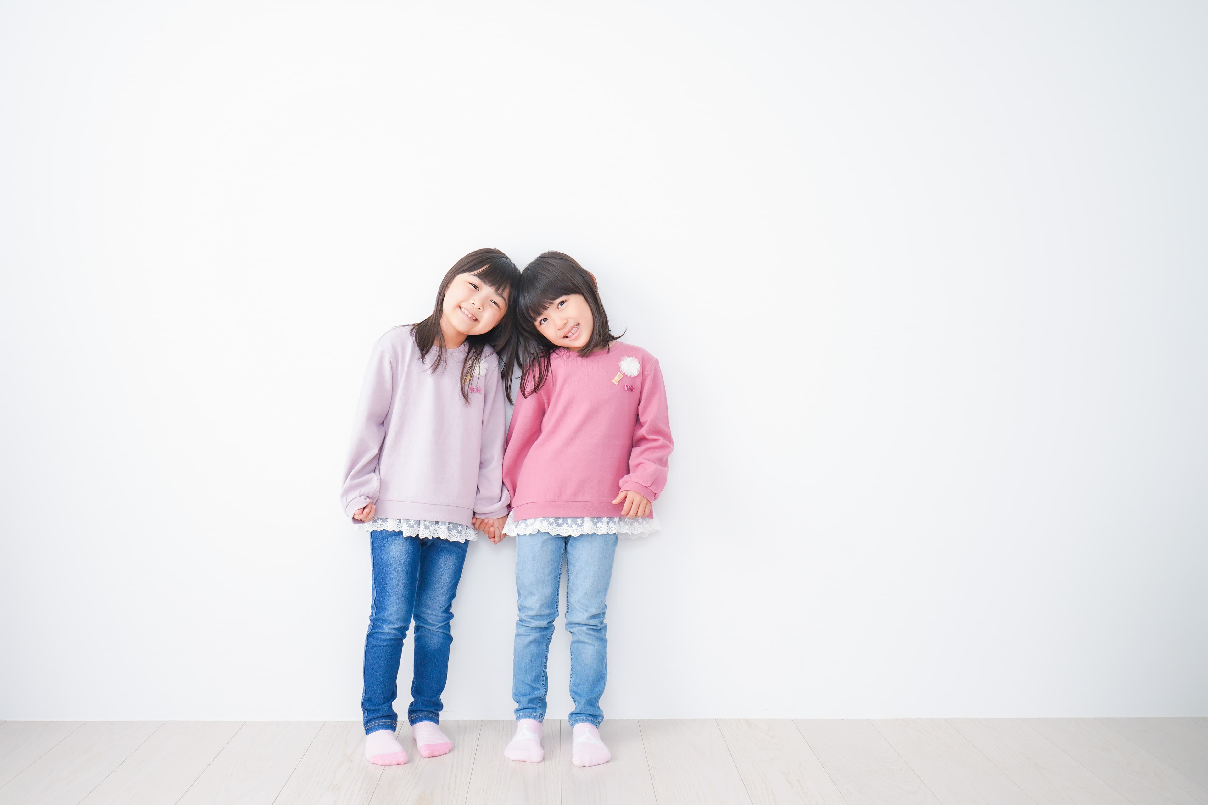 Two smiling children holding hands against a white background