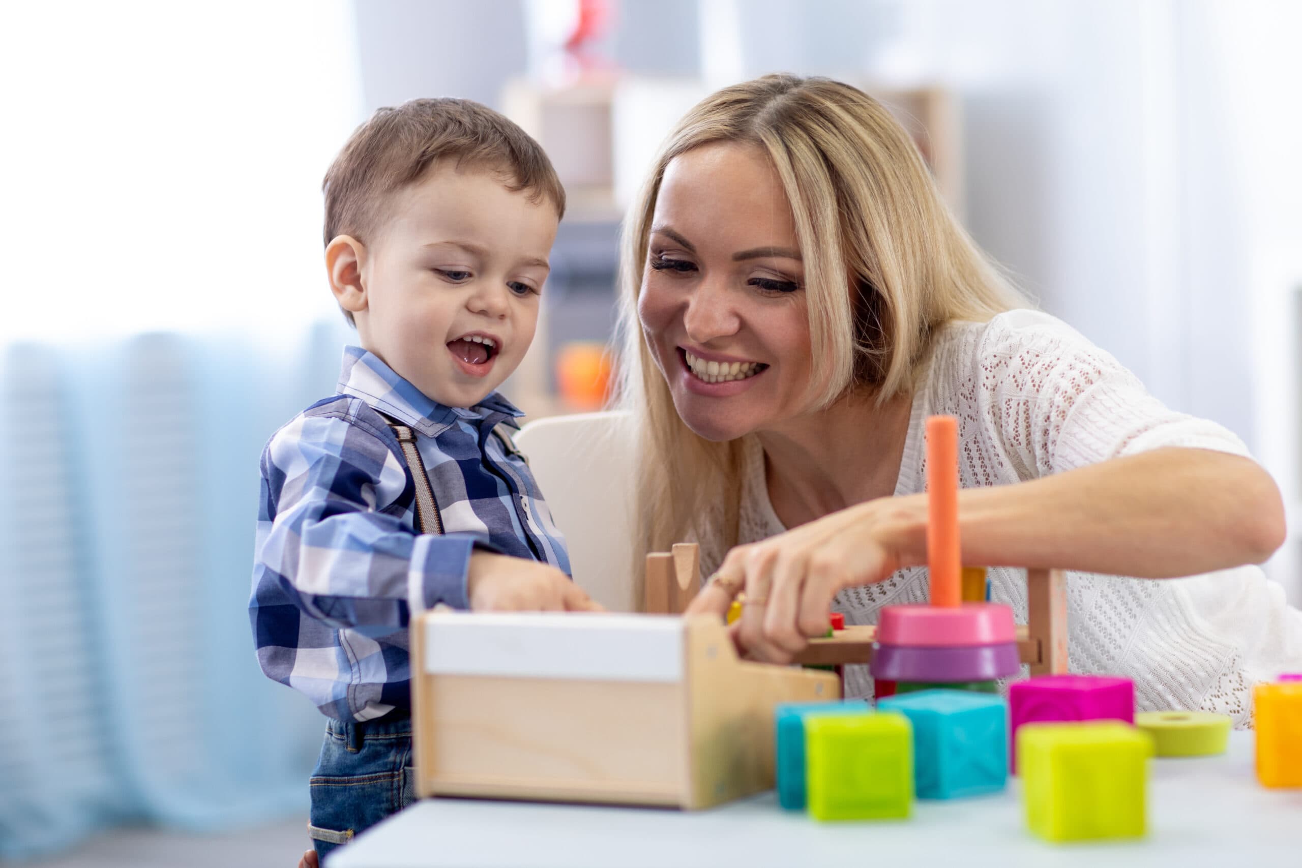 Women and young boy playing with kids toys, smiling.