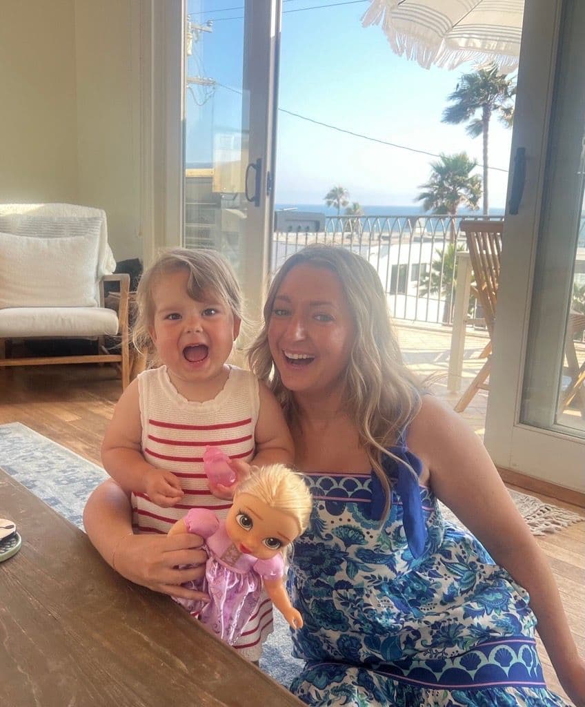 Erin Connelly and toddler smiling with a doll