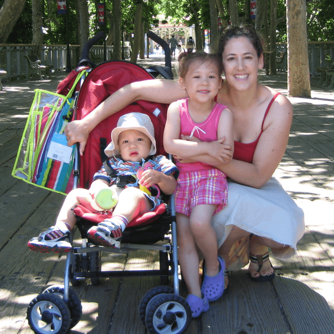 First Steps for Kids Director of Operations Karyn Lew kneeling with two children