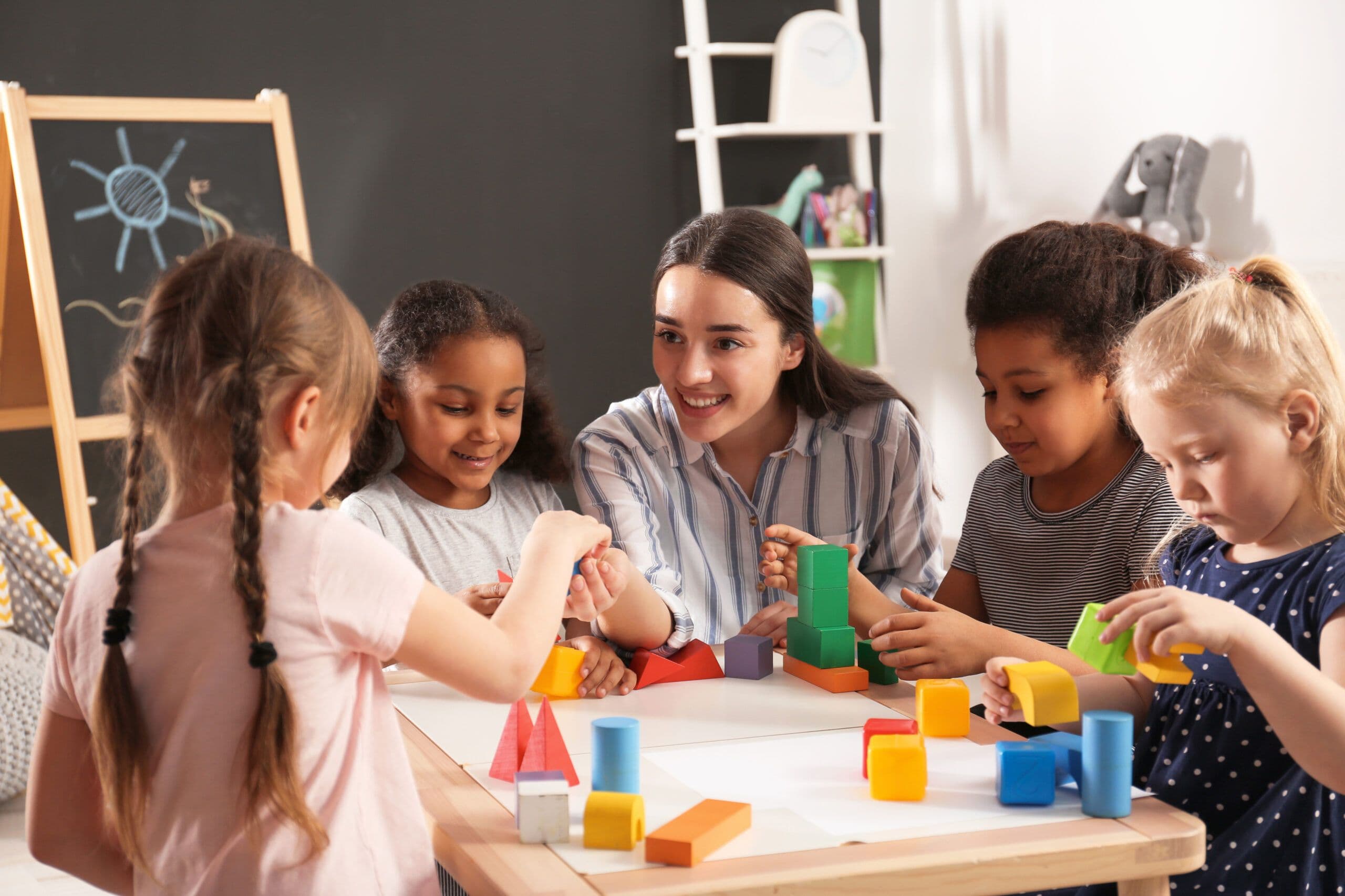 Toddlers and a teacher playing with blocks in a daycare