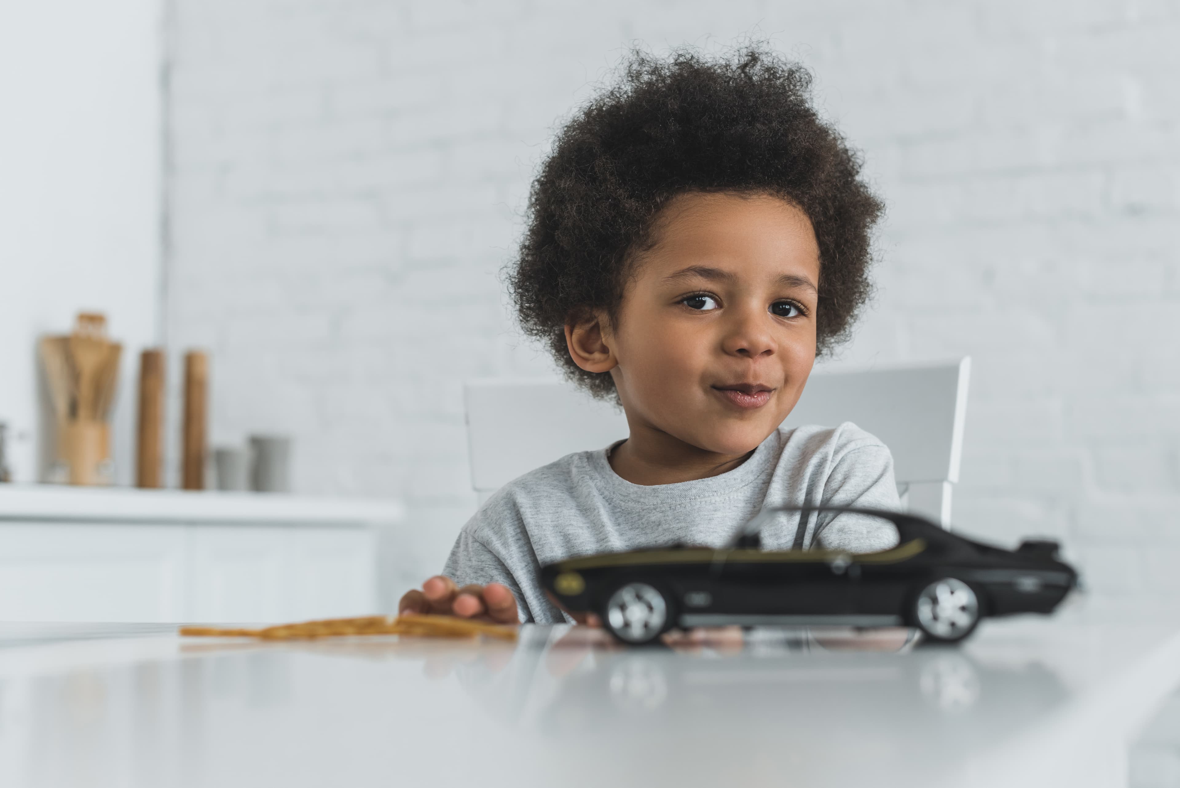 A child looking at the camera with a toy car in the foreground