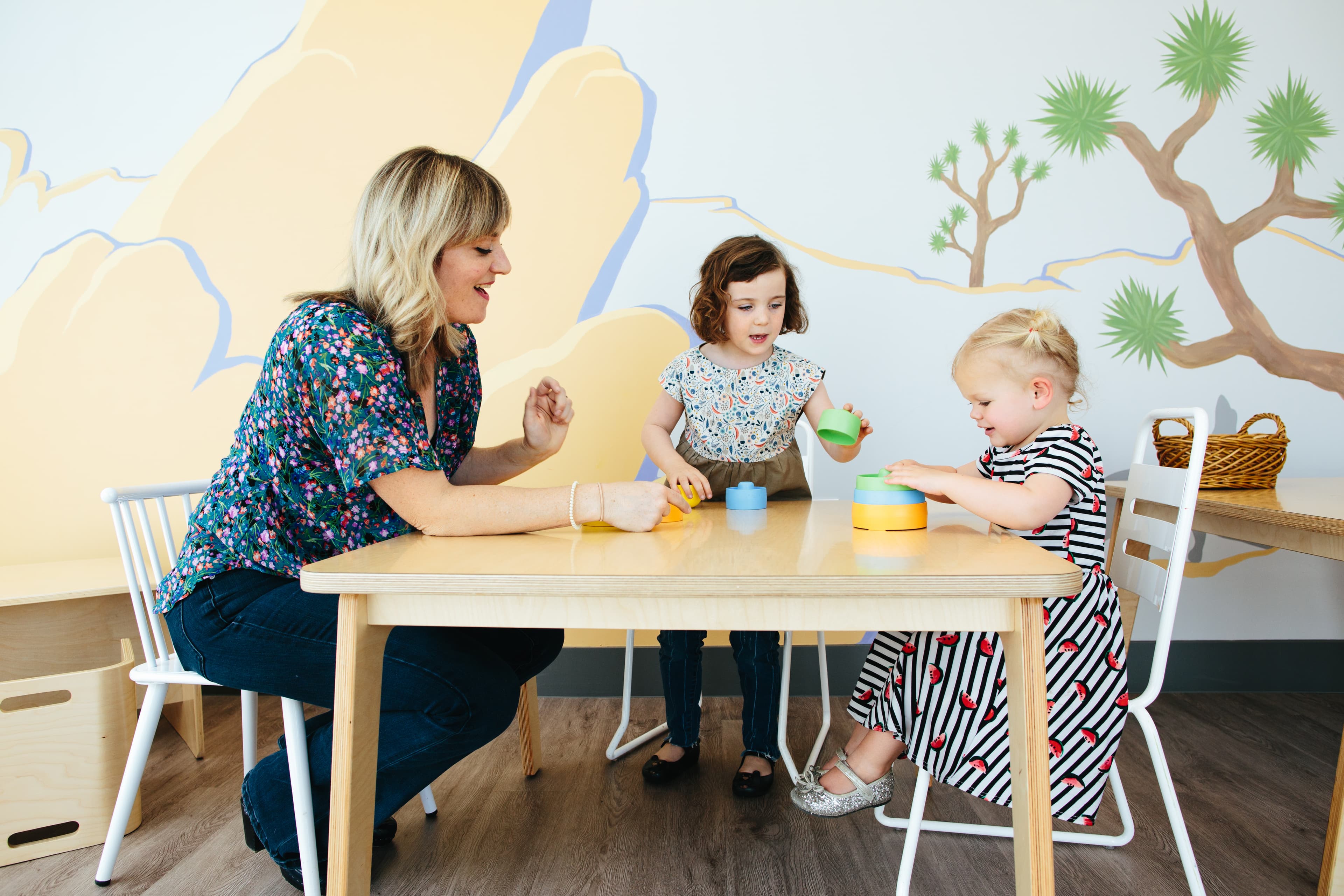 An adult and two children playing with stacking blocks at a table