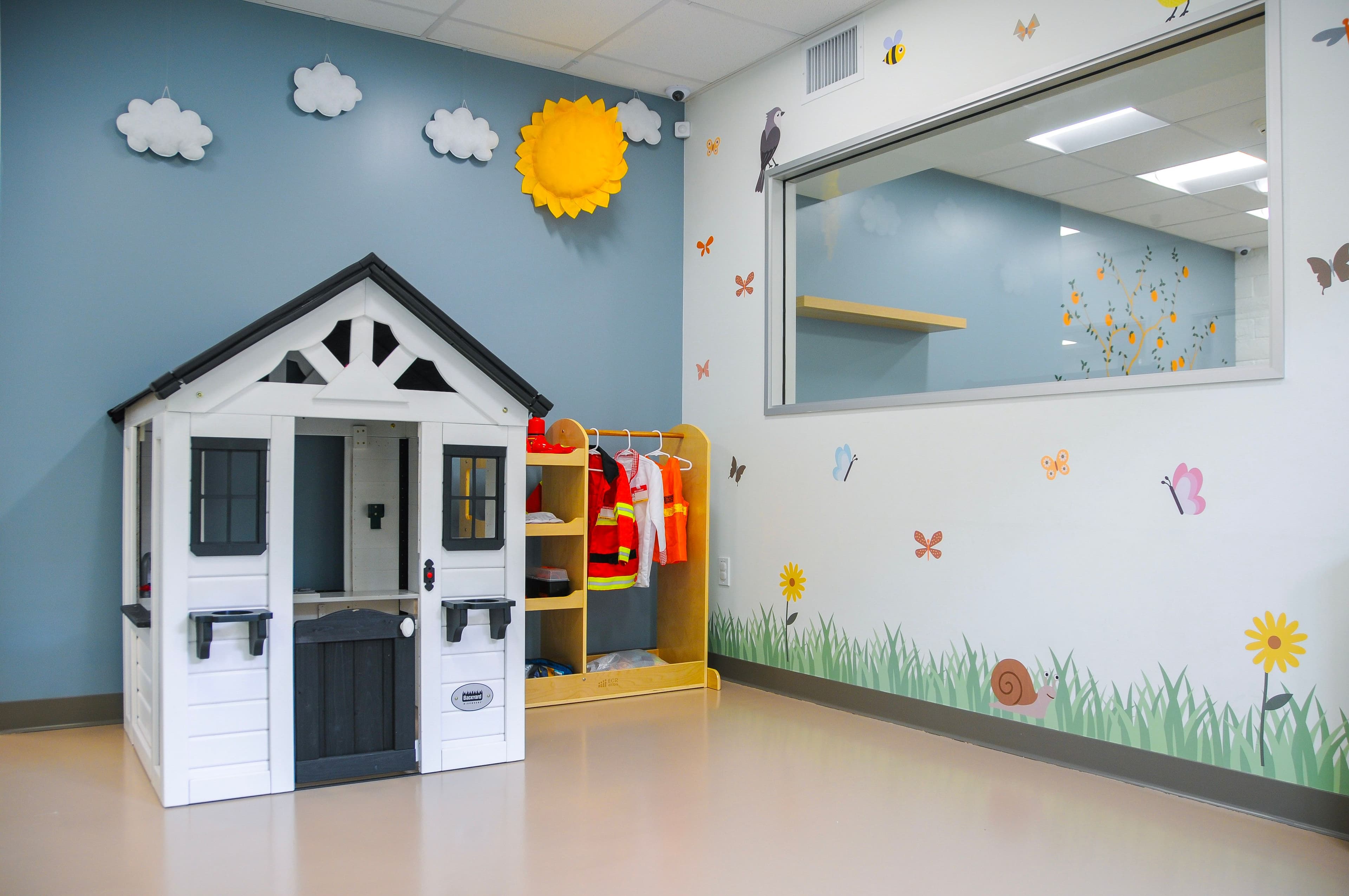 A brightly colored kids play room lined with cubbies of toys with bright sunlight from tall windows on the left